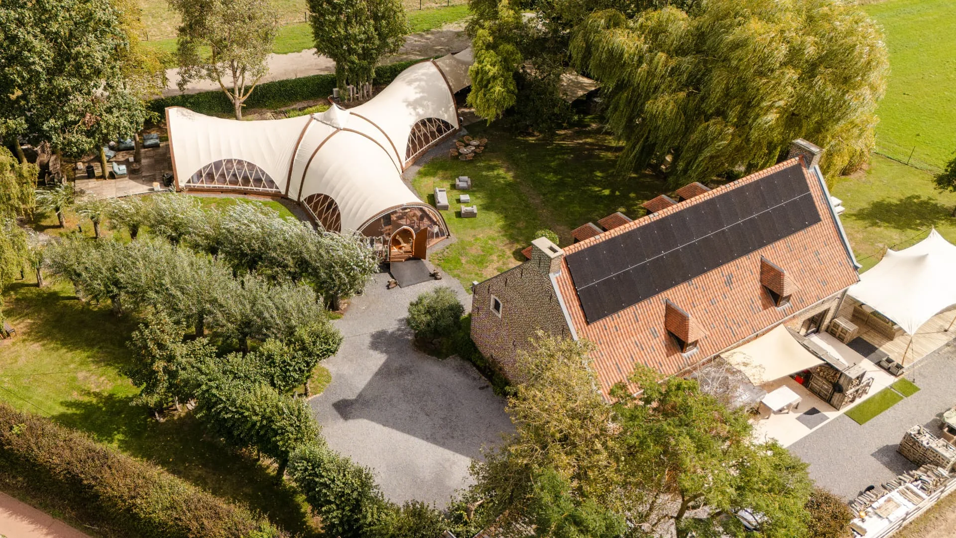 Luchtfoto van het paviljoen, de historische hoeve en het omliggende groene terrein